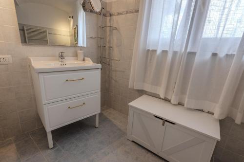 a white bathroom with a sink and a mirror at Maison Orange - Dimora nelle Langhe in Neive