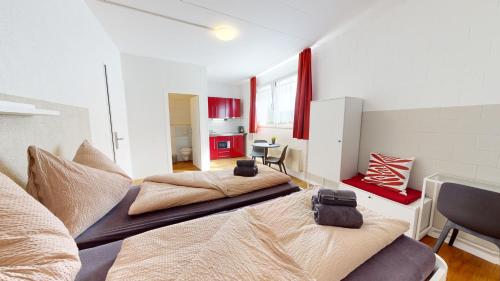 two beds in a room with red and white at Anstatthotel Cham - self-check-in in Cham