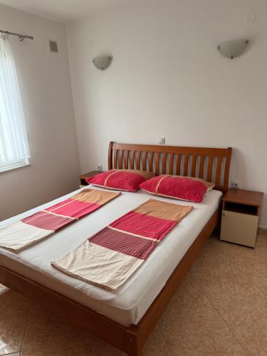 a bed in a room with two red pillows on it at Villa Mane in Donji Štoj