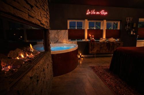 a bathroom with a tub and a fire place at Wellness Tuin - Boudoir Suite - Ultieme Partner Beleving - Indoor Jacuzzi en Openhaard en privé Sauna - in Romantische stijl - Gratis Fles Prosecco & Leuke Partner connect box ! in Horst