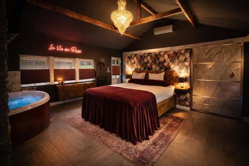 a bedroom with a bed and a bath tub at Wellness Tuin - Boudoir Suite - Ultieme Partner Beleving - Indoor Jacuzzi en Openhaard en privé Sauna - in Romantische stijl - Gratis Fles Prosecco & Leuke Partner connect box ! in Horst