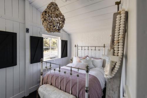 a bedroom with a bed and a chandelier at Bushy Summers - A Nurturing Bayside Shack in Strahan