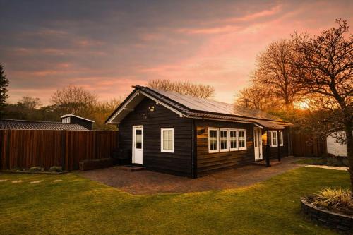 a small house in a yard with a fence at Wellness Tuin - Ultieme Partner Beleving - St Hubertus Suite met Indoor Jacuzzi, Openhaard, Privé Hottub en Privé Sauna in Jachthut stijl - Gratis Fles Prosecco & Leuke Partner connect box ! in Horst