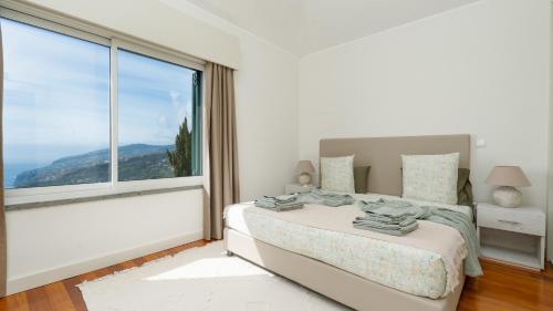 a bedroom with a bed and a large window at DuskLine Villa by LovelyStay in Arco da Calheta