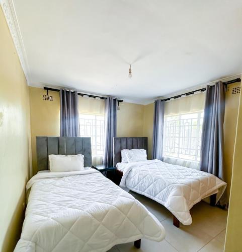 two beds in a room with two windows at The Residence in Lilongwe