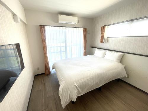 a bedroom with a white bed and a window at コンドミニオ久貝 in Miyako-jima