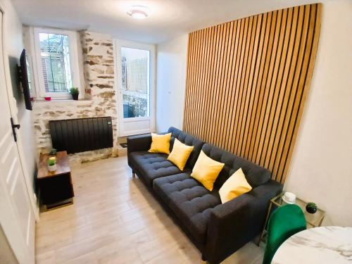 a living room with a black couch with yellow pillows at L Oasis Cosy Sauna Privé et Jardin in Bouguenais