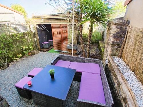 a patio with a blue table and purple benches at L Oasis Cosy Sauna Privé et Jardin in Bouguenais