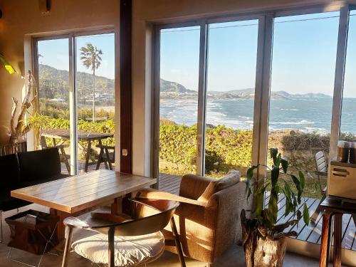 a living room with a table and a view of the ocean at Guest House & Beach Cafe fuego in Hyuga