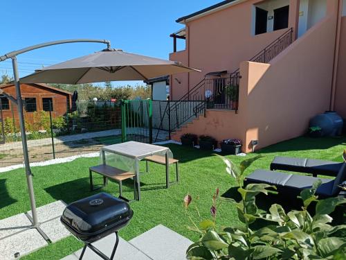a patio with an umbrella and a table and a grill at Raggio di Sole in Campofelice di Roccella