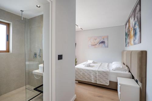 a white bedroom with a bed and a bathroom at Blue Bay Hotel in Sarandë