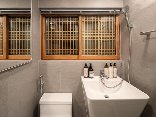 a bathroom with a sink and a toilet and a window at Luxury Hanok On169 in Seoul