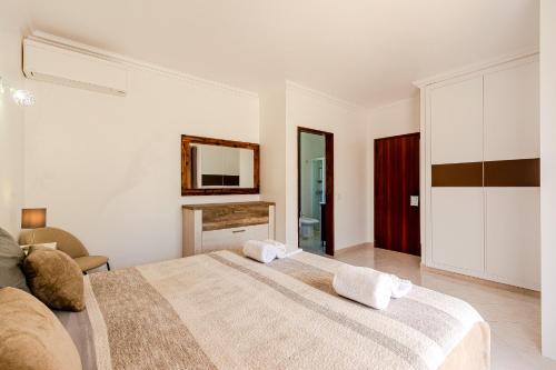 a white bedroom with a large bed and a mirror at Villa Orange with private pool Albufeira in Albufeira