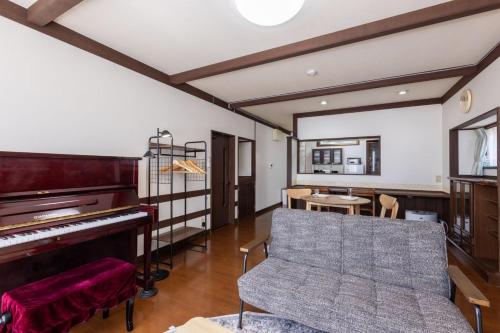 a living room with a piano and a table at Irest Village Matsumoto 2 in Matsumoto