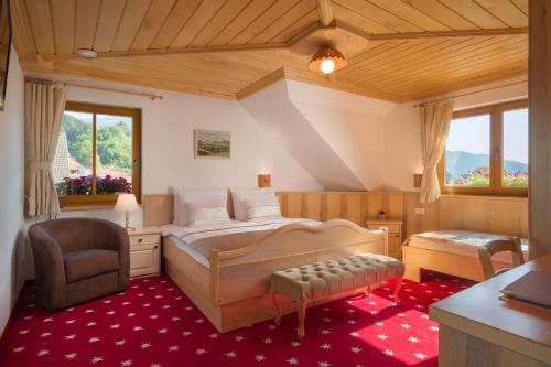 a bedroom with a bed and a chair and windows at Hotel Planinka in Ljubno