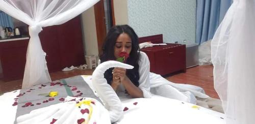 a woman is sitting on a bed with a swan at Fidel Hotel in Bahir Dar