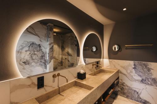 a bathroom with two sinks and two mirrors at Hotel Alte Post Südsteiermark in Leibnitz