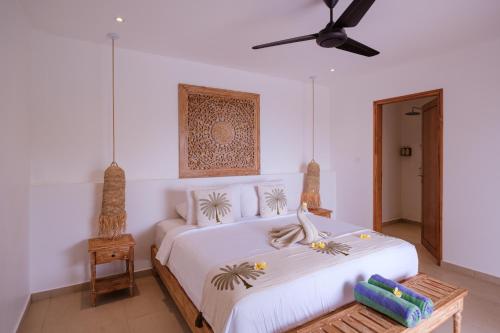 a bedroom with a white bed with a ceiling fan at Bukit Adi in Amed