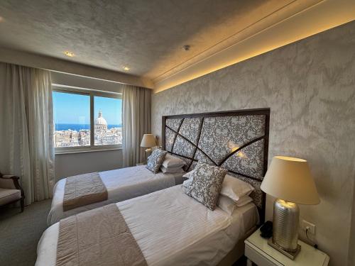 ein Hotelzimmer mit zwei Betten und einem Fenster in der Unterkunft Osborne Hotel in Valletta