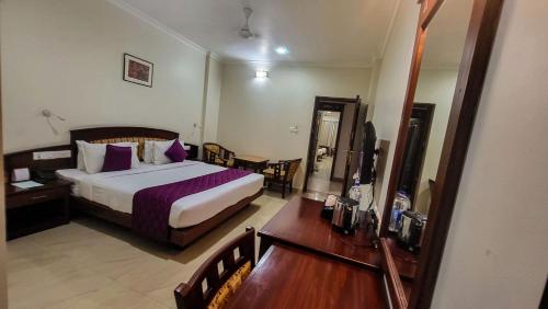 a bedroom with a bed and a table and a mirror at Hotel White City in North Paravur