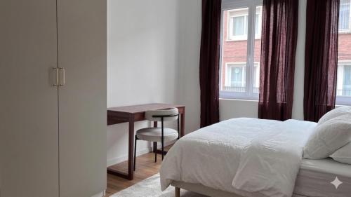 a bedroom with a bed and a desk and a window at Cocon de Charme - T2 sur Place d'Armes in Valenciennes
