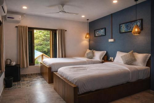 a bedroom with two beds and a window at EKAM in Agonda