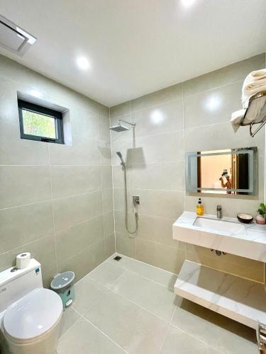 a bathroom with a toilet and a sink and a mirror at KIMO HOUSE Khem Beach in Phú Quốc