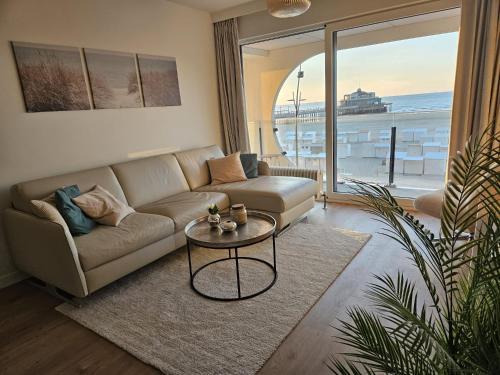 a living room with a couch and a table at Isola Bella - Luxe Verblijf op de Zeedijk met Panoramisch Uitzicht in Blankenberge