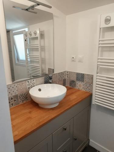 a bathroom with a white sink on a wooden counter at Petite Maison a deux pas du centre in Le Faou