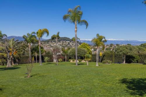 a park with palm trees and a city in the background at REF 2193 - Super Cannes Villa for rent in Vallauris