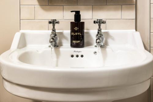 a bathroom sink with a bottle of soap on it at Wheatsheaf Inn in Brigsteer