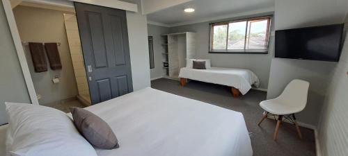 a bedroom with two beds and a tv and a chair at Gables B&B Guesthouse in George