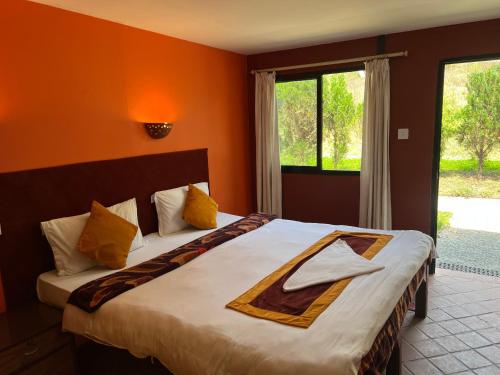 a bedroom with a large bed with orange walls at Dakshinkali & Dollu Resort in Pharping