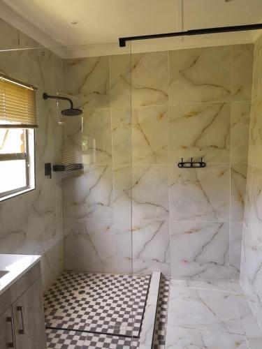 a bathroom with a shower with white marble walls at B Cubed Lodge in Port Shepstone