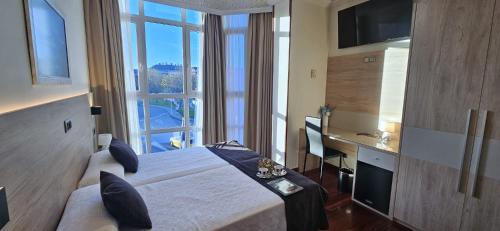 a hotel room with a bed and a desk and window at Hotel Nueva Plaza in Maliaño