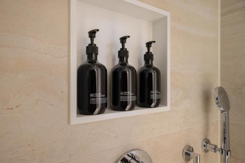 three black bottles sitting on a shelf above a sink at Grand Hotel Huis ter Duin in Noordwijk aan Zee