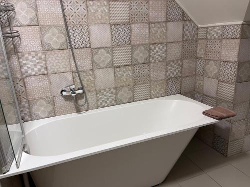 eine weiße Badewanne in einem gefliesten Badezimmer in der Unterkunft Stikāni in Bernāni