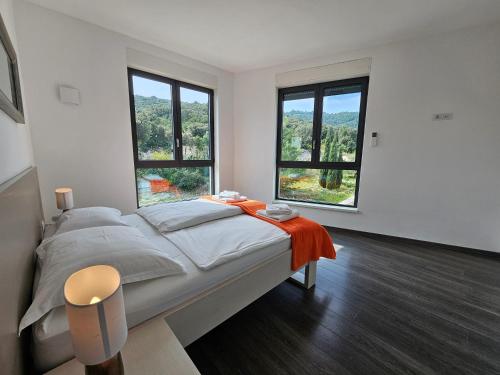 a bedroom with a large bed with two windows at Korcula Holiday in Korčula