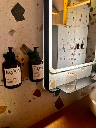 two bottles of soap on a wall in a bathroom at Le Vert d'Orezza in Valliquerville