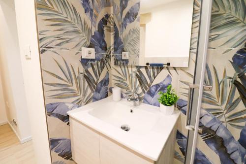 a bathroom with a sink and a leafy wallpaper at Penelope's House in Otranto in Otranto