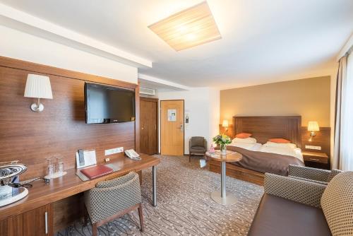 ザルツブルクにあるオーストリア クラシック ホテル ヘレのベッドとデスクが備わるホテルルームです。