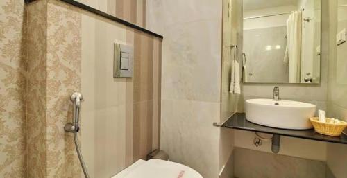 a bathroom with a sink and a toilet and a mirror at Hotel Sepoy Grande in Mysore