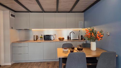 a kitchen with white cabinets and a wooden table at Antresola - Apartamenty Parkowe in Gniezno