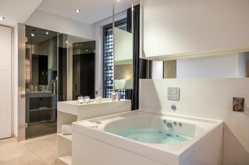 a white bathroom with a tub and a sink at Hotel SB Plaza Europa in Hospitalet de Llobregat