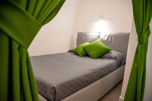 a bed with green pillows in a room at Trullo Fico d'India in Alberobello
