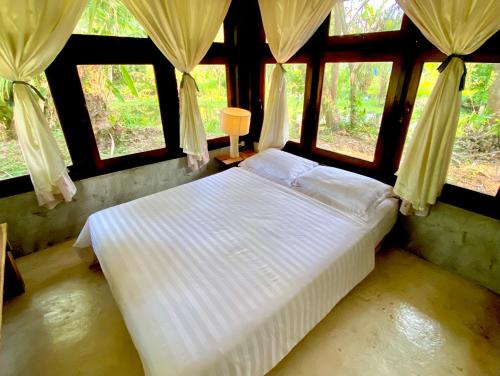 a bedroom with a bed in a room with windows at Latehouse bar Amphawa in Amphawa