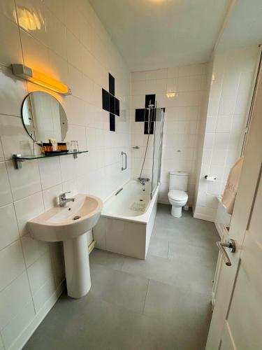 a bathroom with a sink and a tub and a toilet at Royal Sportsman Hotel in Porthmadog