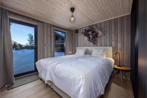 a bedroom with a white bed and a large window at Lakelodge 10p in Vradal