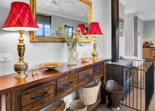 a wooden dresser with two lamps and a mirror at River Verse in Porepunkah