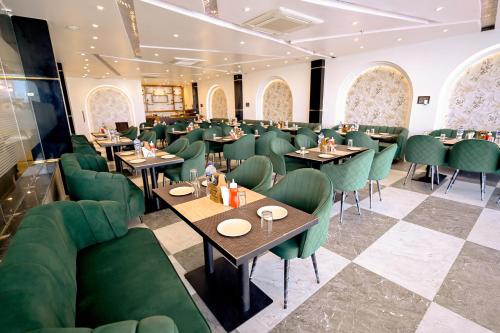 a dining room with green chairs and tables at Madhuram Hotel in Ayodhya